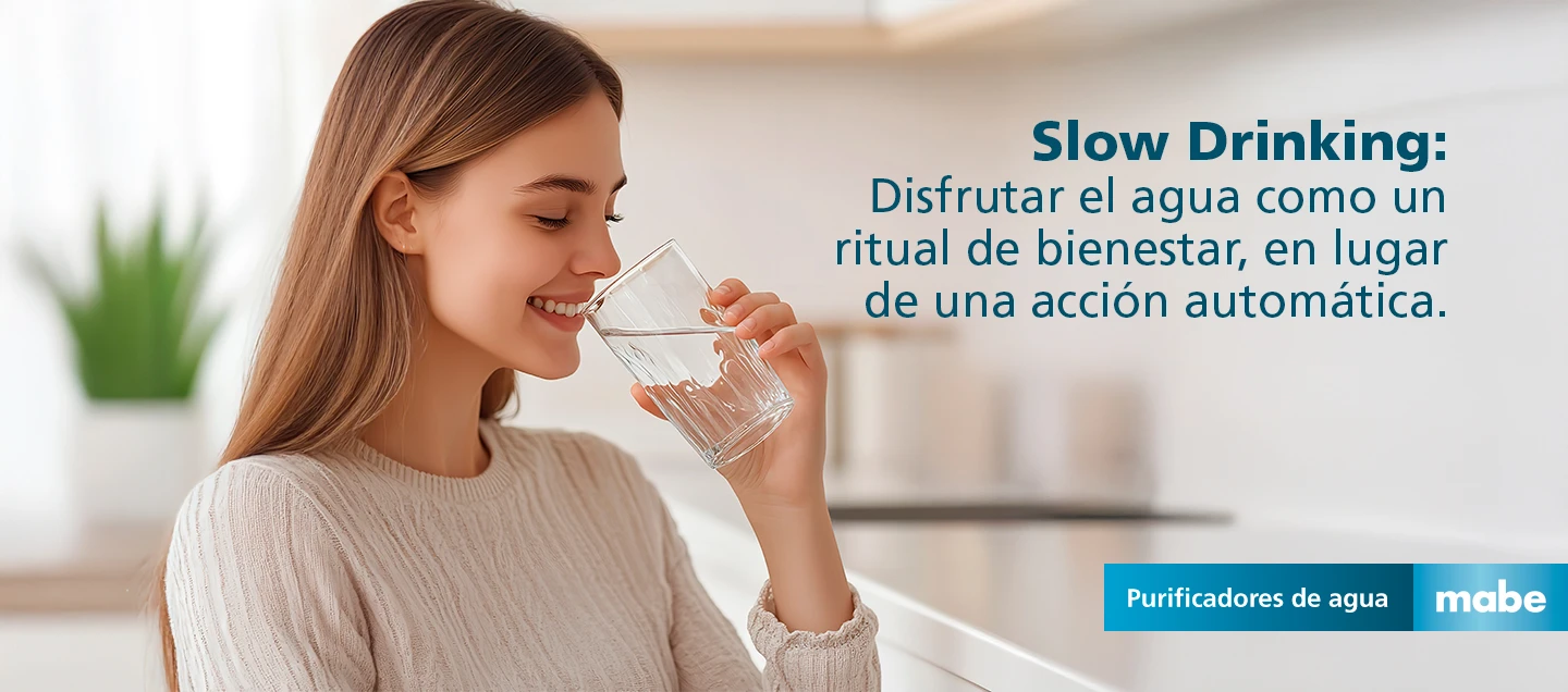 Mujer sonriendo mientras bebe agua, con el texto 'Slow Drinking: Disfrutar el agua como un ritual de bienestar'. Campaña de purificadores de agua mabe